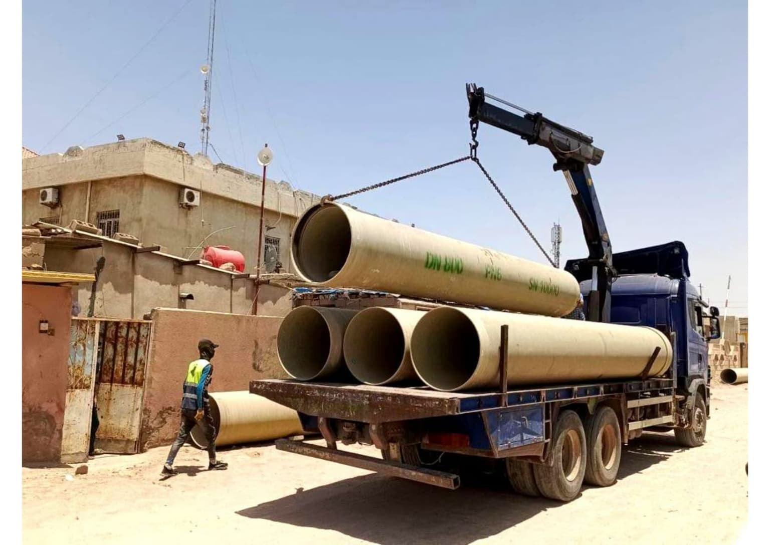 شاحنة برافعة تُنزل أنابيب GRP كبيرة قياس DN 800 في الموقع