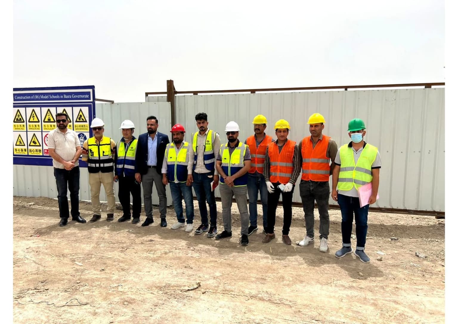 مجموعة من المهندسين والعمال أمام لوحة مشروع المدارس النموذجية