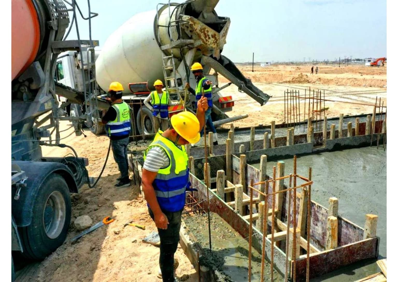 Concrete poured from a mixer truck into a reinforced strip-footing formwork